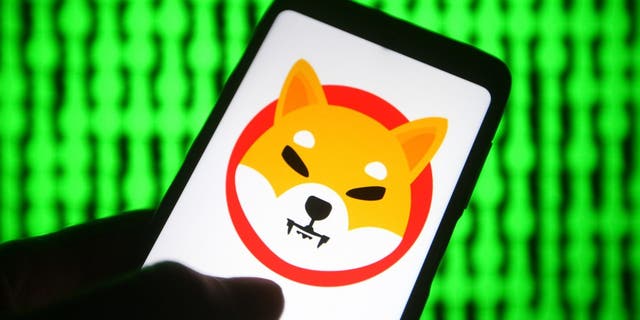 اوکراین - 03/06/2021: در این تصویر تصویری، آرم رمز ارز Shiba Token $SHIB (Shiba Inu) روی گوشی هوشمند با صفحه نمایش کامپیوتر در پس زمینه دیده می شود.